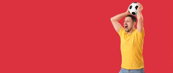 Emotional man with soccer ball on red background with space for text - Foto, Imagen