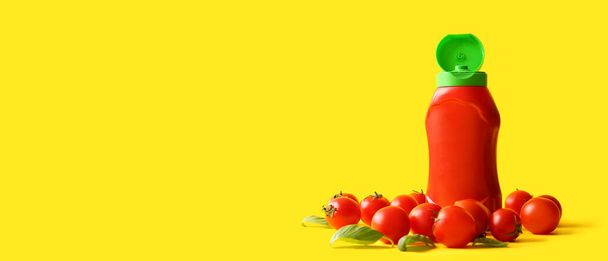 Fles ketchup en tomaten op gele achtergrond met ruimte voor tekst - Foto, afbeelding
