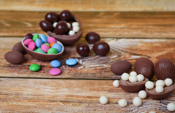 Delicious chocolate eggs and candies on wooden table - Zdjęcie, obraz
