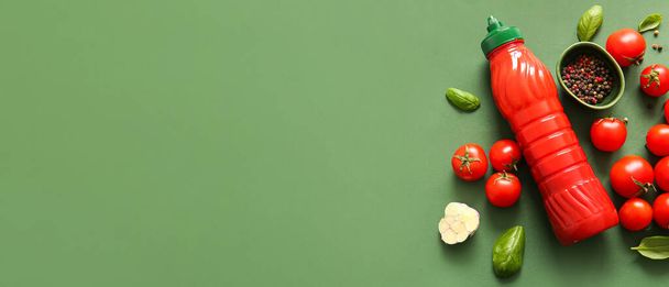 Bottiglia di ketchup, spezie e pomodori su sfondo verde con spazio per il testo - Foto, immagini