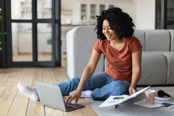Boldog fekete Szabadúszó nő dolgozik laptop és papírok otthon, mosolygó afro-amerikai nő ül a padlón a nappaliban, és a számítógép használata, élvezi a távoli Online munka, másolás tér - Fotó, kép