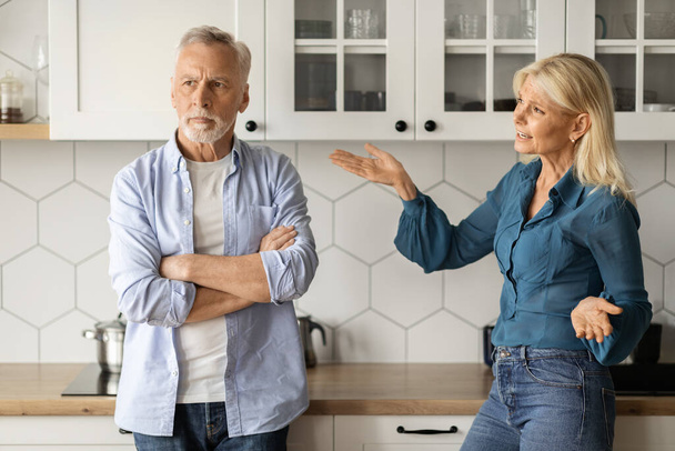 Εσωτερικές συγκρούσεις. Πορτρέτο του ηλικιωμένου ζευγαριού που μαλώνει στο εσωτερικό της κουζίνας, θυμωμένη ώριμη κυρία που φωνάζει στο σύζυγό της στο σπίτι, ηλικιωμένοι σύζυγοι που υποφέρουν από κακή κατανόηση και συζυγική κρίση, κοντινό πλάνο - Φωτογραφία, εικόνα