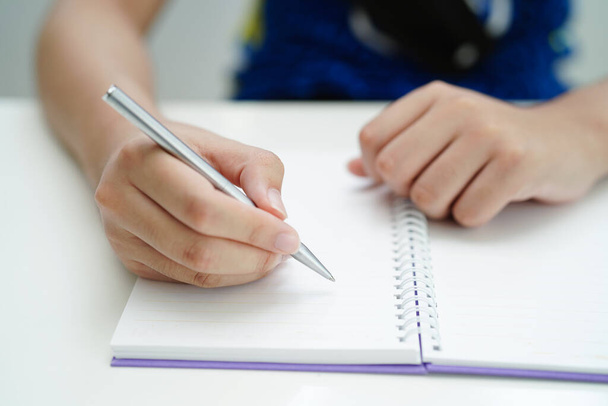 Азиатский студент-подросток пишет домашнюю работу, изучает уроки для экзамена онлайн обучения. - Фото, изображение