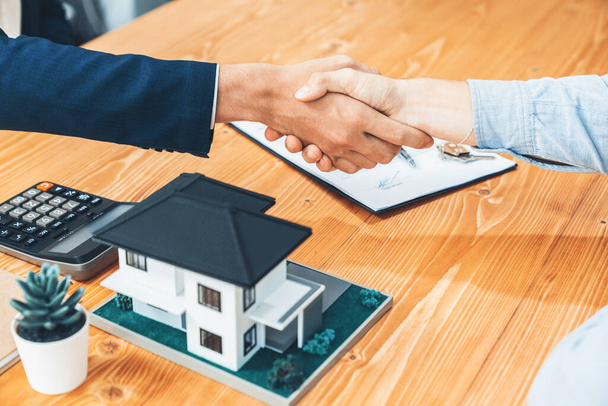 Finalizing house loan agreement with handshake, buyer and real estate agent celebrate accomplishment of property ownership with sense of satisfaction. New home owner shake hand with broker. Entity - Фото, зображення