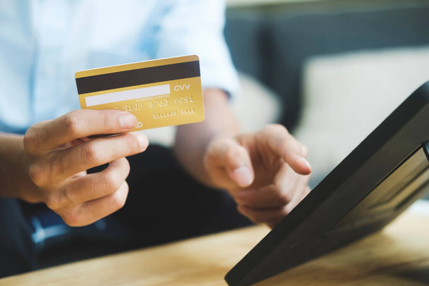 Een jonge zakenman hand houden credit card en met behulp van laptop thuis, online winkelen en betalen rekeningen, Betaalmethode. - Foto, afbeelding