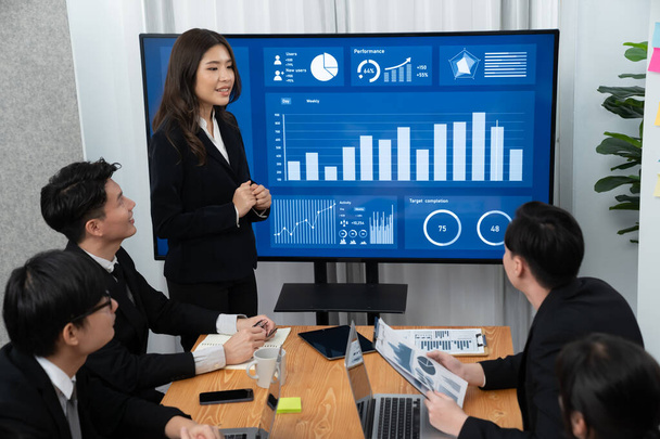 Confidence and young asian businesswoman give presentation on financial business strategy in dashboard report display on screen to colleagues in conference room meeting as harmony in workplace concept - Foto, Bild