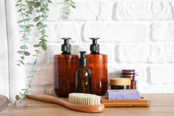 Bath accessories with massage brush on table near white brick wall - Φωτογραφία, εικόνα