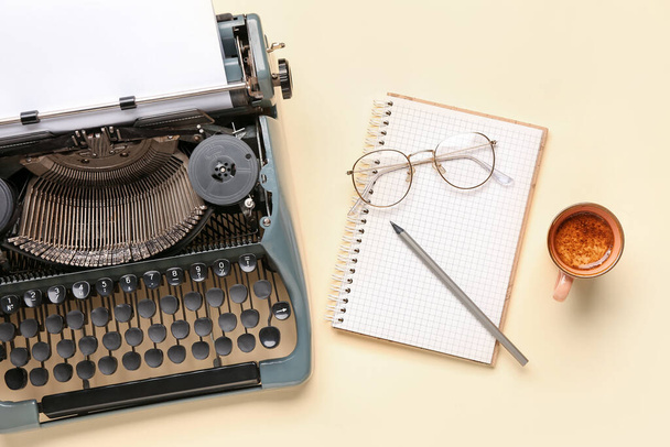 黒紙シート、眼鏡、ノート、鉛筆、黄色の背景にコーヒーカップとヴィンテージタイプライター - 写真・画像