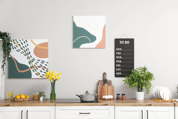 Интерьер стильной кухни с цветущими нарциссами в вазе на прилавке - Фото, изображение