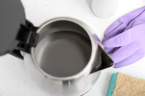 Electric kettle with limescale and purple rubber gloves on white table, closeup - Foto, immagini