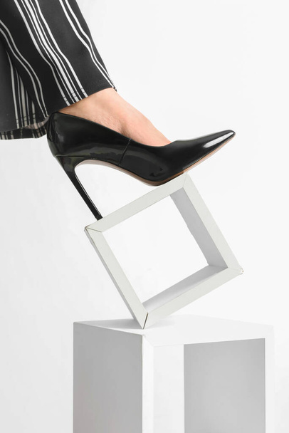 Female leg in black heels standing on stand against white background - Photo, image
