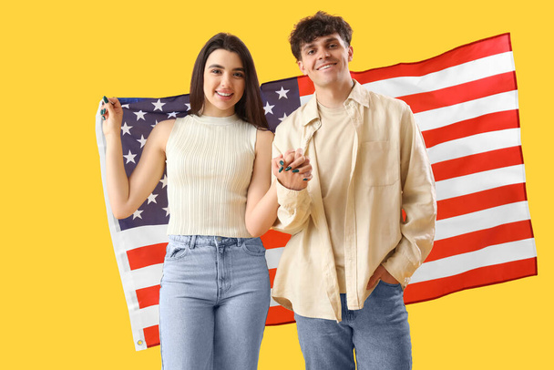 Young couple with USA flag on yellow background - Photo, Image