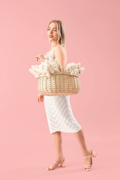 Young woman with basket of lilac flowers on pink background - Foto, Imagem