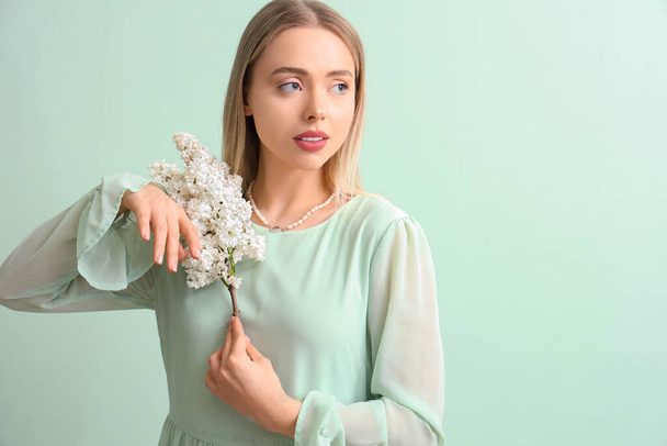 Young woman with lilac flowers on green background - Photo, Image