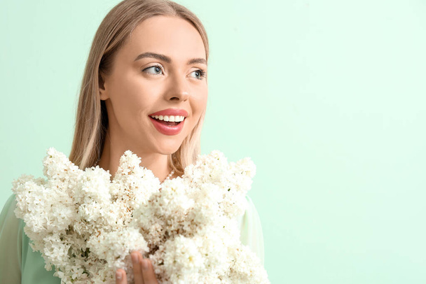 Young woman with lilac flowers on green background, closeup - Фото, зображення