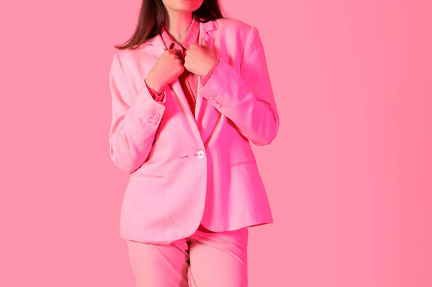 Young woman in stylish suit on pink background - 写真・画像