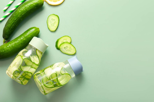 Sports bottles of infused water with cucumber slices on green background - Fotografie, Obrázek