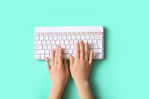 Female hands with modern computer keyboard on turquoise background - Photo, Image