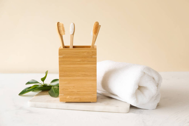 Bamboo tooth brushes in holder and towel on light background - Zdjęcie, obraz