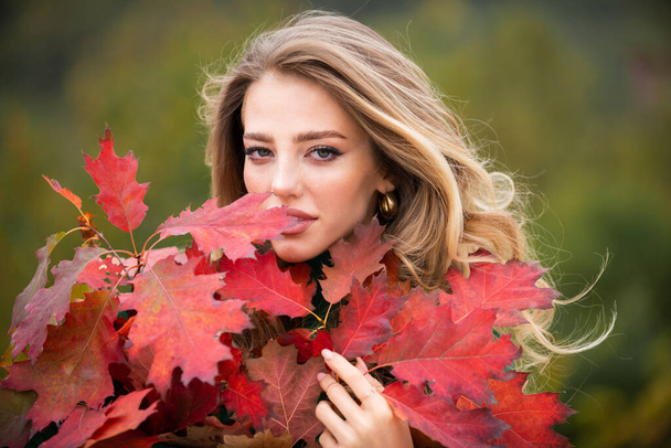Autumn fall. Portrait young woman with autumn leafs on foliage. Beautiful girl outdoor in autumn. Sensual woman with yellow leaves in autumn. Pretty woman with leaf near face on autumnal background - Fotoğraf, Görsel