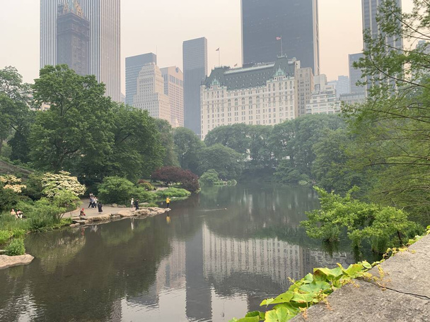 Central Park-NYC Under Wildfire Smoke dal Canada. 7 giugno 2023, New York, USA: Una nuvola di fumo raggiunge gli Stati Uniti dal Canada, dove centinaia di incendi colpiscono il paese. Gli Stati Uniti hanno lanciato avvertimenti per le popolazioni vulnerabili a rimanere al chiuso. - Foto, immagini