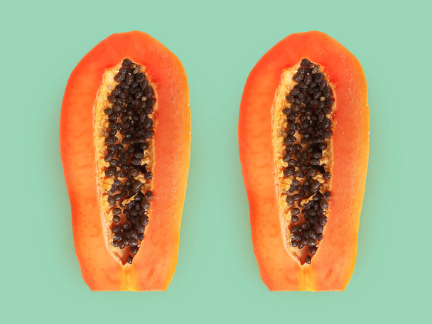 Half of ripe papaya fruit with seeds on a color background. Appetizing tropical fruit - Foto, afbeelding