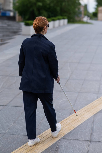 Blind businesswoman walking along tactile tiles with a cane - Photo, Image