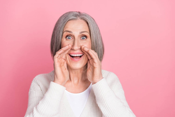 Portrait of positive funky aged lady arms near mouth whisper tell private information isolated on pink color background. - 写真・画像