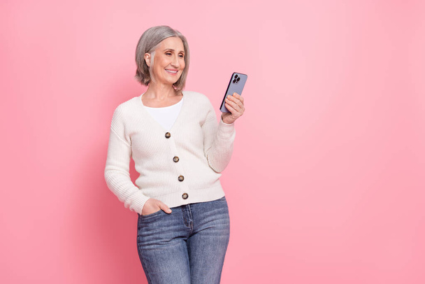 Photo of senior woman hold device use instagram telegram twitter facebook wear trendy white clothes isolated on pink color background. - Φωτογραφία, εικόνα