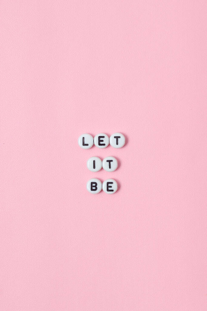 Bovenaanzicht van "let it be" citaten gemaakt van kralen op roze achtergrond. motivatie en succesconcept - Foto, afbeelding