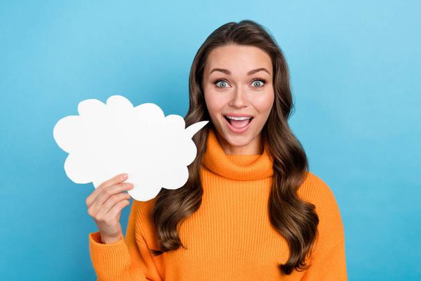 Photo of adorable excited woman wear orange sweater holding speaking cloud emtpy space isolated blue color background. - Foto, afbeelding