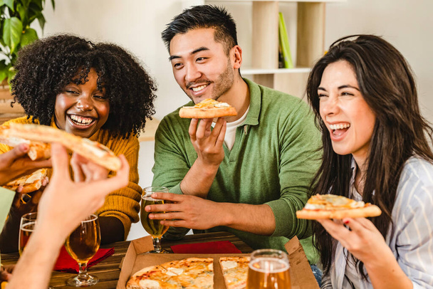 Gruppe junger multiethnischer Mitarbeiter, die sich in einem Restaurant treffen. Pizza essen und Bier trinken - Abendessen mit Freunden zu Hause- - Foto, Bild