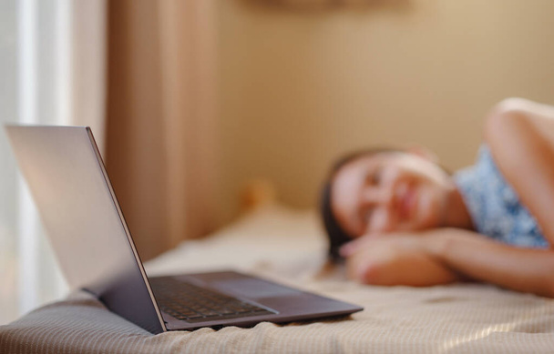 Gelukkige jonge Aziatische vrouw met laptop rustend in slaapkamer in klein huis, weekendje weg en afgelegen kantooridee. Kleine huizen en Small Living concept. - Foto, afbeelding