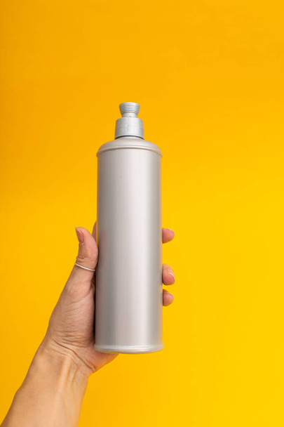 Grey shampoo bottle on a yellow background - Zdjęcie, obraz