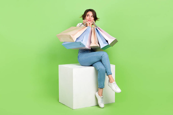 Full length photo of excited dreamy lady wear white crop top holding shoppers looking empty space isolated green color background. - Foto, afbeelding