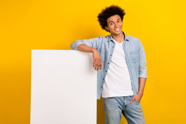 Portrait of cheerful handsome man demonstrate empty space novelty placard isolated on yellow color background. - Foto, Imagen