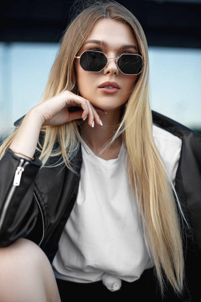 a beautiful girl in a leather jacket and black glasses near a sh - Foto, imagen