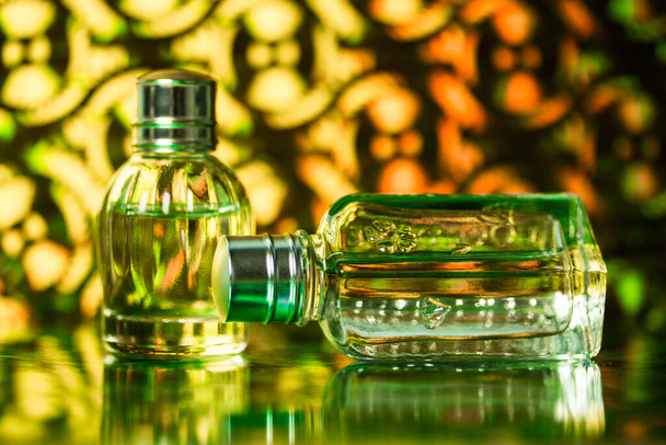 Unbranded perfume bottles on green yellow background. A glass bottle of eau de toilette fragrance water. No brand female cosmetic advertisement. Toiletry for women. Beauty product wallpaper. - Foto, Imagen
