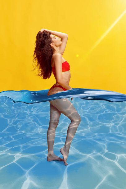 Uvolněná mladá žena s štíhlým tělem ve stylových pohodlných plavkách proti žlutému pozadí s vodním designovým prvkem. Koncept léta, módy, ženské krásy, dovolená, životní styl, reklama - Fotografie, Obrázek
