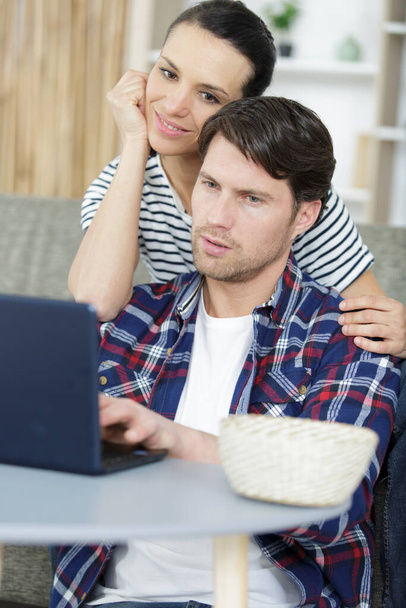 young happy couple using laptop in their apartment - Фото, изображение