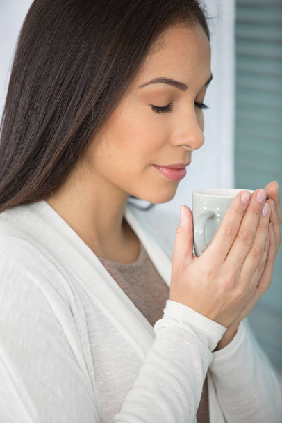 a woman enjoys smelling coffee - Фото, изображение