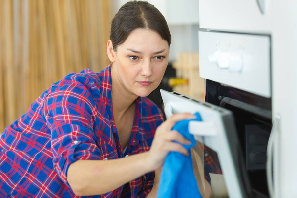 woman cleaning oven with rag - Zdjęcie, obraz