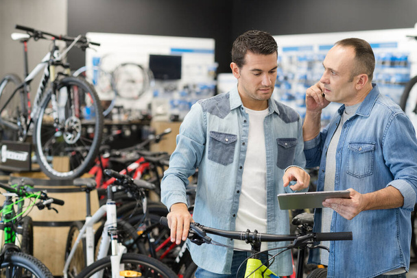 positive guy hiring bike at rental store - Photo, image