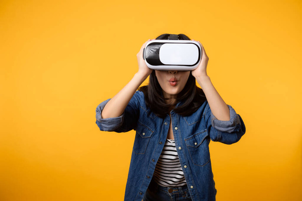 Asian young woman happy success wearing virtual reality headset game entertainment isolated on yellow background. Winner of cyber future video game concept. - Foto, Bild