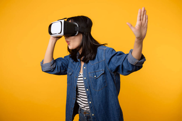 Aziatische jonge vrouw gelukkig succes met het dragen van virtual reality headset game entertainment geïsoleerd op gele achtergrond. Winnaar van cyber toekomstige video game concept. - Foto, afbeelding