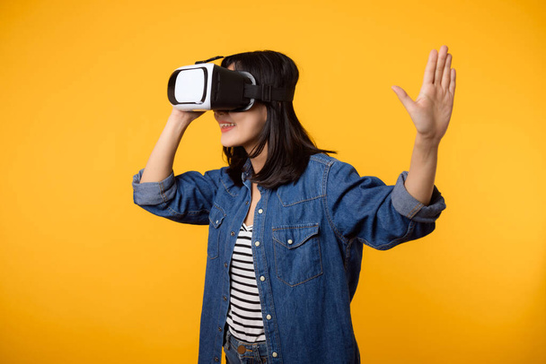 Asiática jovem mulher feliz sucesso vestindo realidade virtual headset entretenimento jogo isolado no fundo amarelo. Vencedor do conceito de futuro jogo de vídeo cibernético. - Foto, Imagem