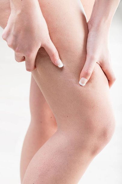 Uma mulher está examinando a textura e tonicidade de suas pernas nuas, verificando sinais de celulite ou retenção de líquidos. - Foto, Imagem