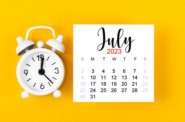 July 2023 Monthly calendar for 2023 year with alarm clock on yellow background. - Zdjęcie, obraz