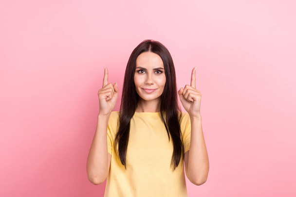 Photo of adorable cute lady wear yellow t-shirt pointing two fingers up empty space isolated pink color background. - Foto, Imagen