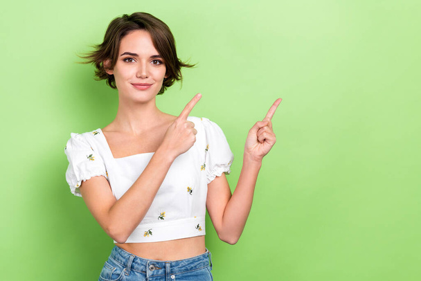 Photo of nice lady promoter direct fingers empty space advise beauty product wear crop shirt isolated green color background. - Fotografie, Obrázek